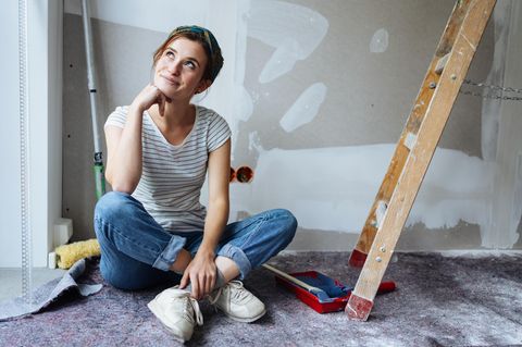 Eine Frau sitzt auf dem Boden eines renovierungsbedürftigen Raumes