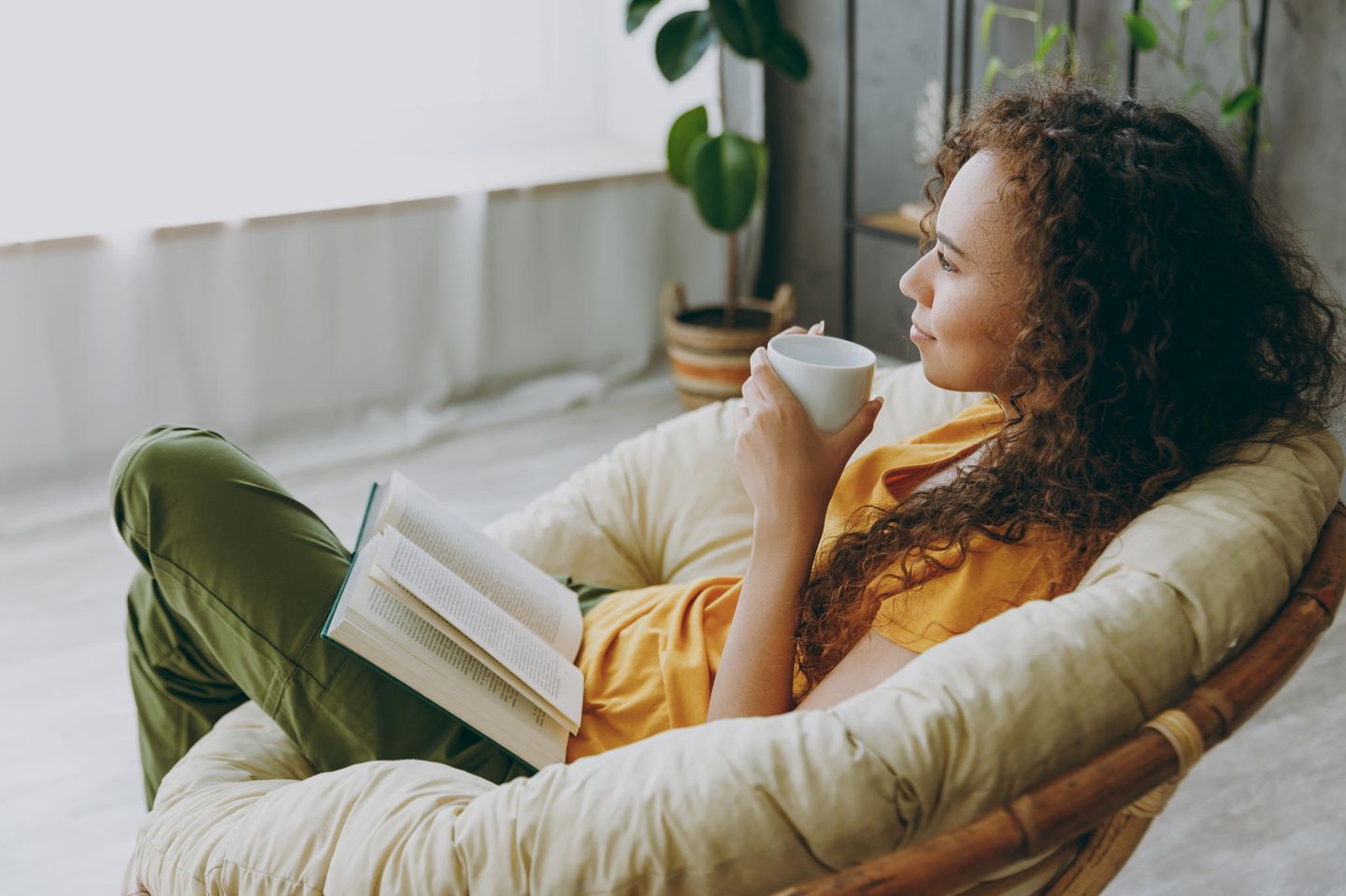 Entspannte Frau liest und trinkt Tee: Das ist die wichtigste Strategie, um mental stark zu sein