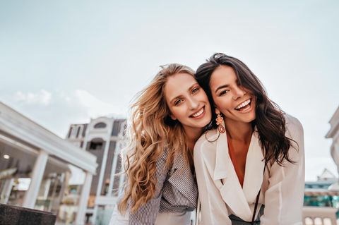 Zwei Freundinnen lachen in die Kamera: Was Menschen aufgrund deiner Gesichtszüge über dich annehmen