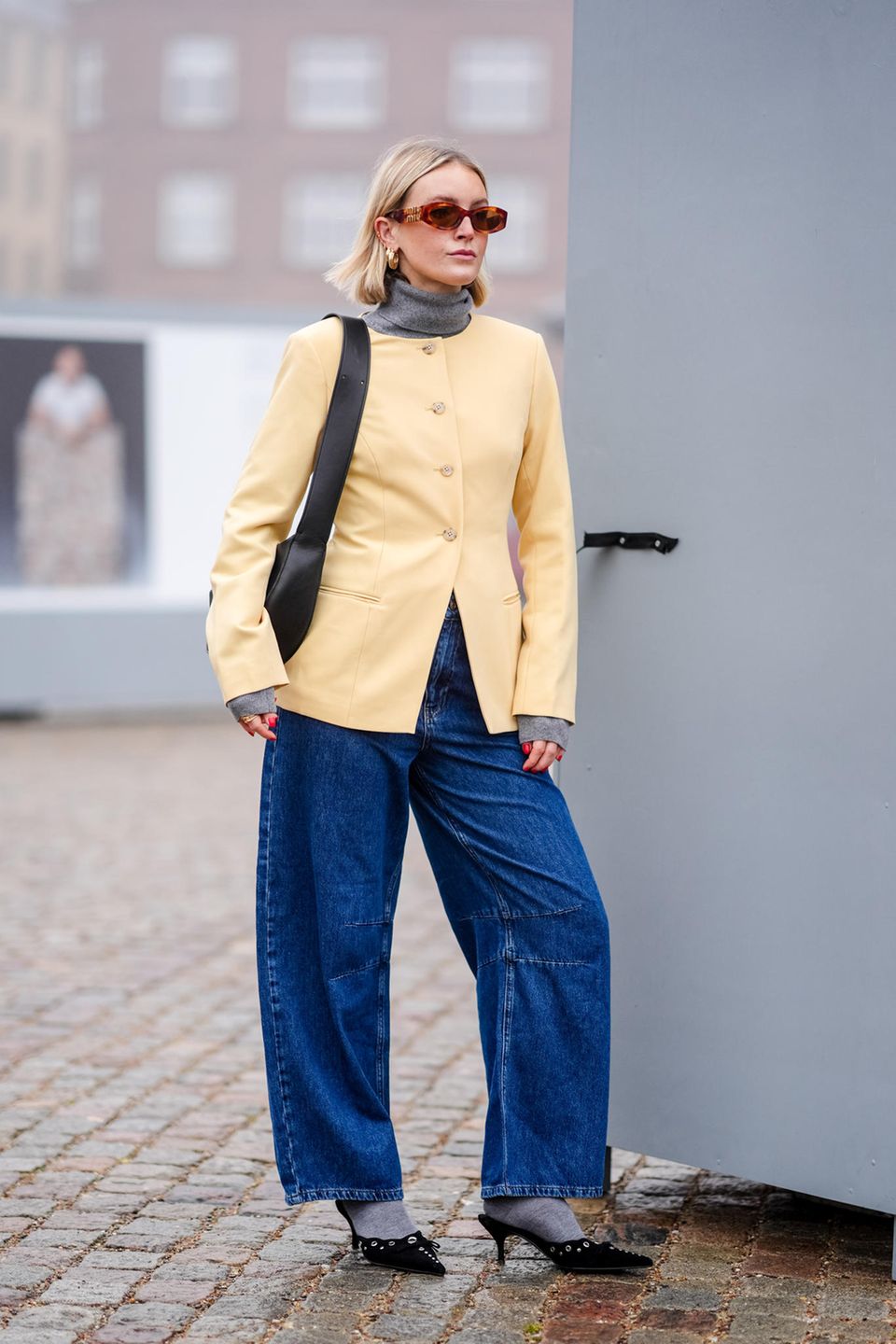 Auch an Tag zwei der Kopenhagener Fashion Week begeistern die Gäste wieder mit ihren Looks. Dieser Gast kombiniert einen grauen Rollkragenpullover mit einer pastell-gelben Jacke und einer Wide-Leg-Jeans. Ihre Socken sind farblich perfekt auf den Pullover abgestimmt, abgerundet wird der Look mit stilvoll gewählten Accessoires.