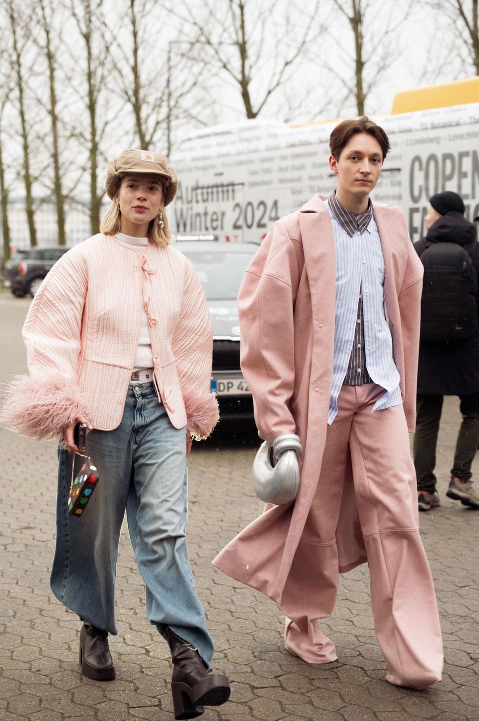 Partnerlook in Altrosa! Dieses stylische Duo besucht die Kopenhagener Fashion Week in abgestimmten Outfits. Sie kombiniert zu ihrer rosafarbenen Jacke eine Wide-Leg-Jeans, die sie in ihre Stiefel gesteckt hat. Ein Hingucker ist die beigefarbene Mütze von Carhartt. Ihr Begleiter trägt eine farblich abgestimmte Kombination aus einer Hose und einem oversized Mantel.