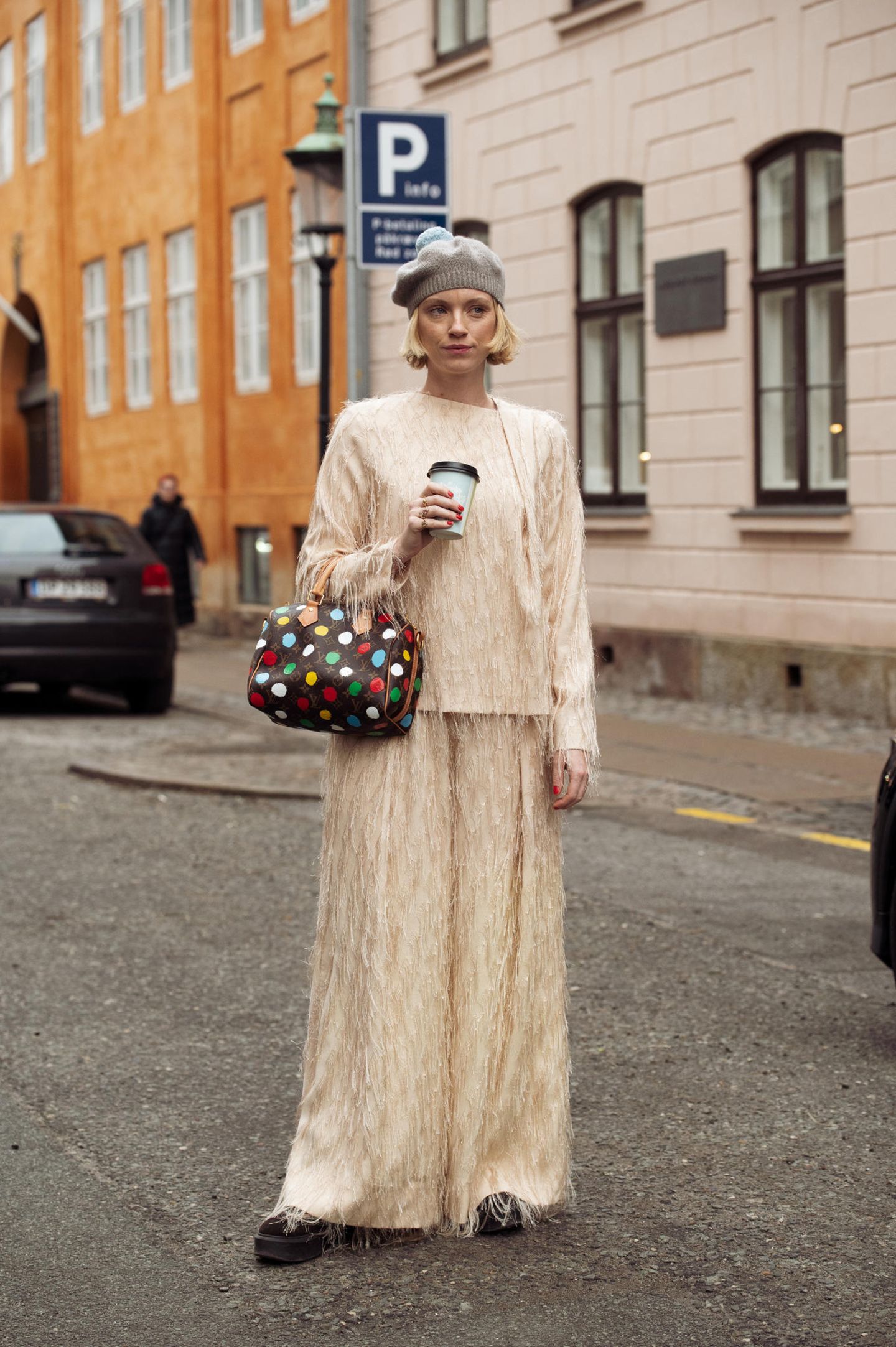 Die Designerin Pernile Rosenkilde besucht die Modenschauen in einem beigefarbenen Zweiteiler mit Fransen. Dazu kombiniert sie eine graue Mütze und eine Louis-Vuitton-Tasche