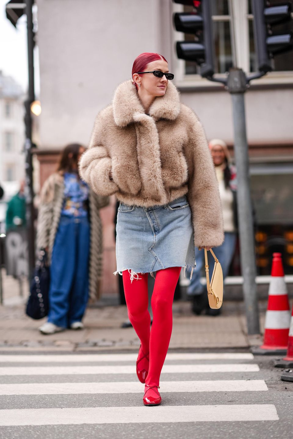 Auch am dritten Tag der Kopenhagener Fashion Week darf eine Fake-Fur-Jacke natürlich nicht fehlen. Marianne Theodorsen wählt eine kurze Version in Beigetönen und kombiniert dazu einen leicht ausgefransten Jeansrock. Das Highlight des Outfits ist ihre knallrote Strumpfhose, die perfekt zu ihren Haaren und ihren Ballerinas passt.