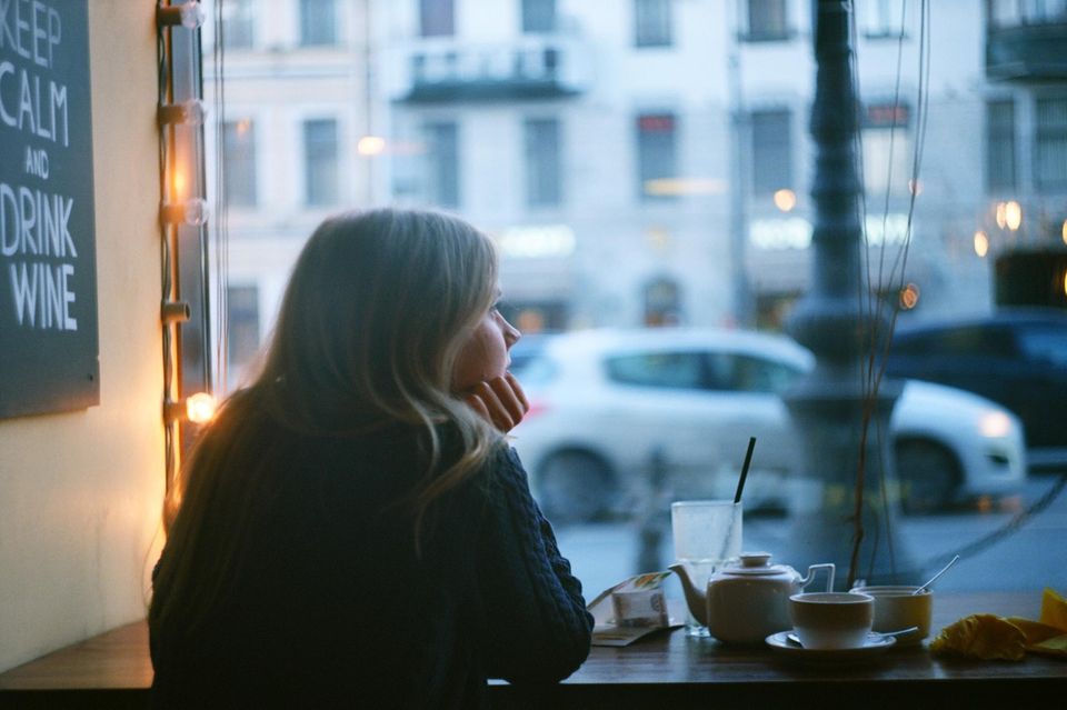 Frau schaut traurig aus dem Fenster: 4 Zeichen, dass dein Leben dich insgeheim langweilt