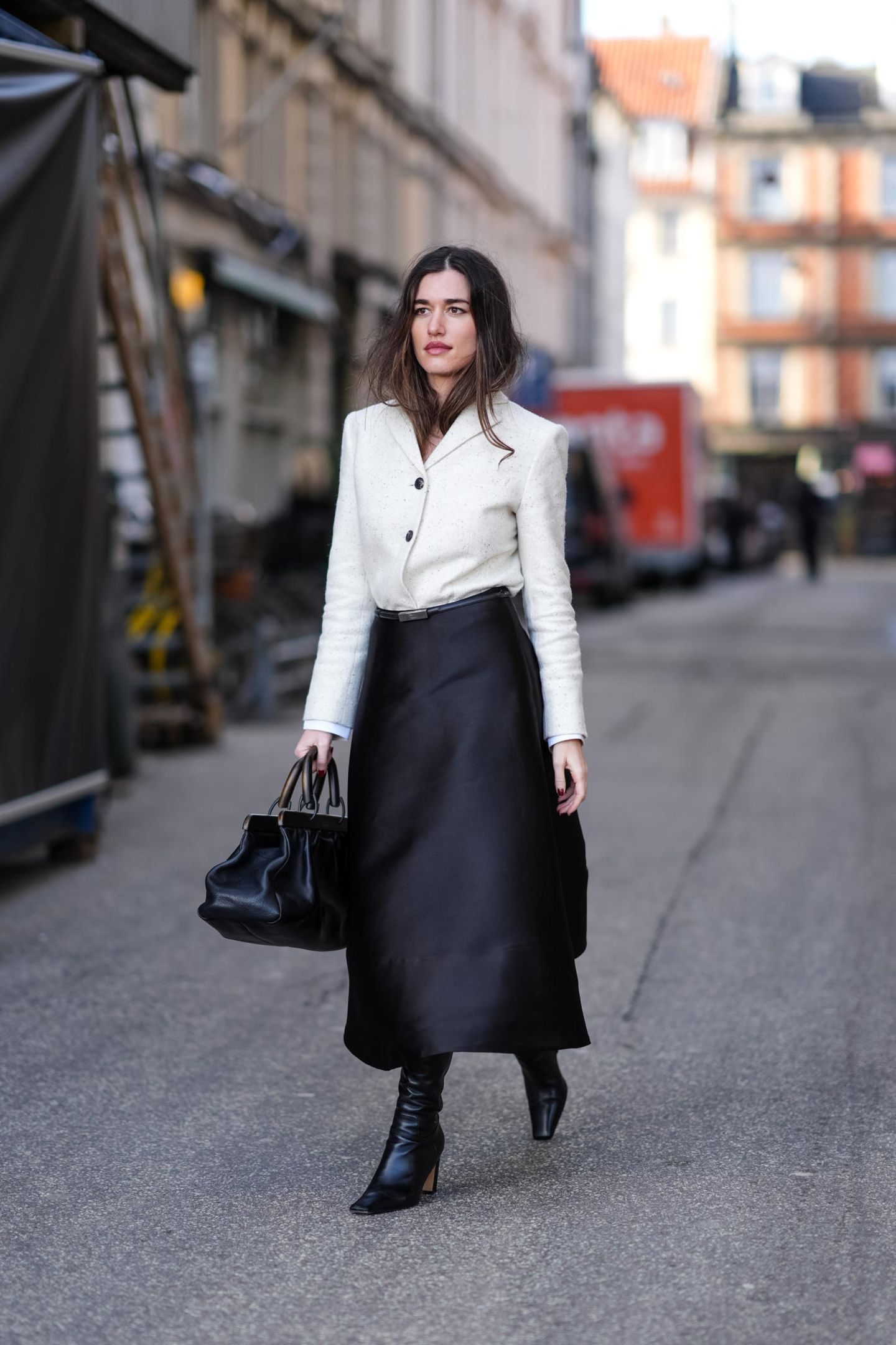 Was ein eleganter Look! In einem schwarzen Satin-Rock und einem weißen Blazer besucht dieser Gast die Fashion Week in Kopenhagen. Abgerundet wird ihr Outfit mit schwarzen Stiefeln und einer schwarzen Tasche, die sie lässig in der Hand trägt. 