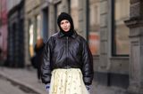 Eine wärmere Outfit-Option wählt Barbora Ondrackova am vierten Tag der Kopenhagener Fashion Week. Sie trägt eine schwarze Bomberjacke in Leder-Optik, die sie zu einem süßen Tüll-Rock kombiniert. Dazu trägt sie eine Baklava-Mütze, eine beigefarbene Tasche und braune Cowboystiefel. Etwas extravaganter ist, dass sie eine fein gestrickte Hose unter dem Rock trägt, die über die Stiefel ragt.