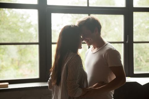 Seelenpartner: Glückliches Paar umarmt sich vor einem Fenster