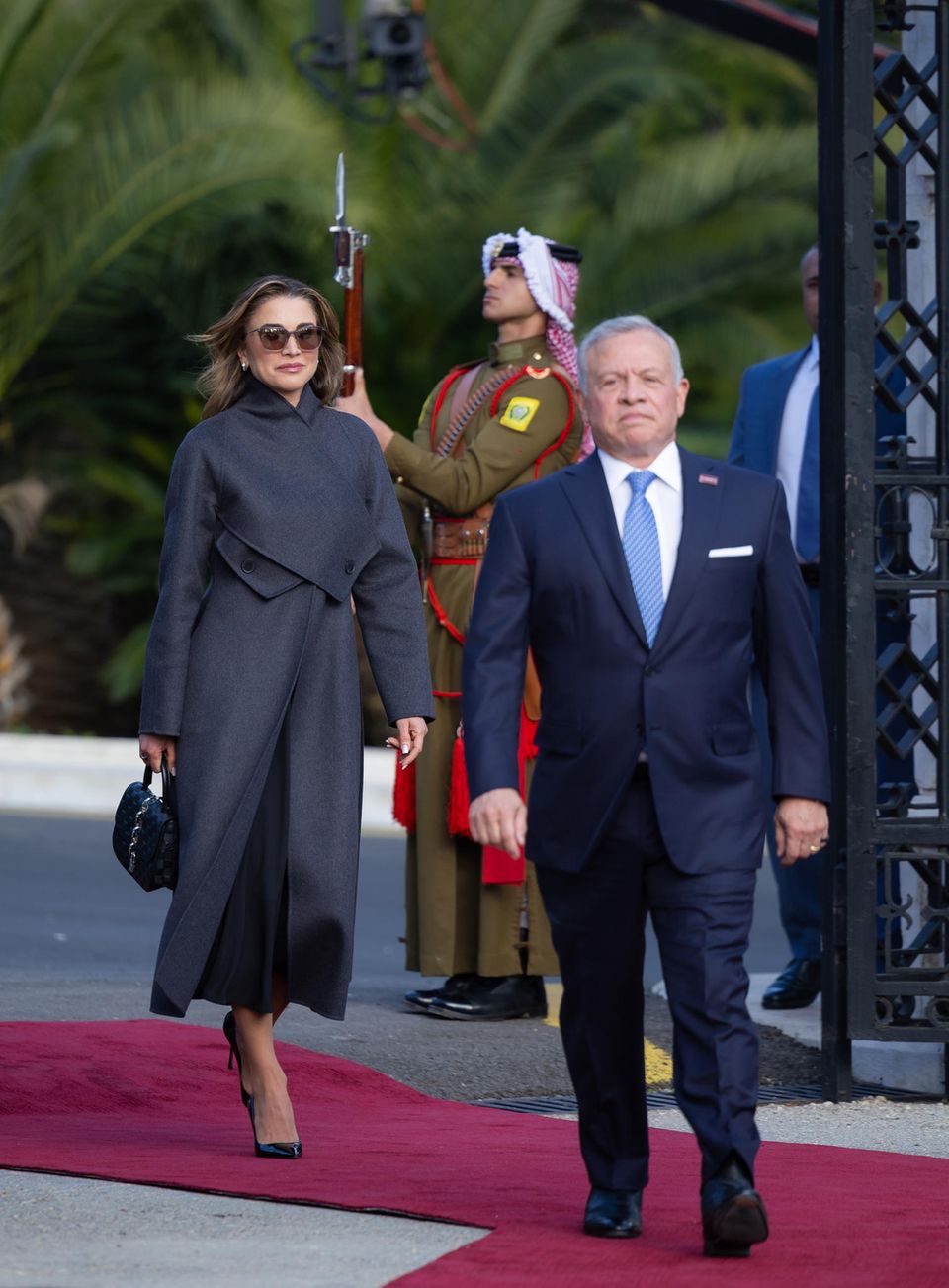 Cool, cooler, Königin Rania: Bei den Feierlichkeiten zum 25. Thronjubiläum in Amman inszeniert sie sich wie eine stylische Geheimagentin im Wollmantel von Dior, mit schwarzer Louis Vuitton Tasche und schwarzer Sonnenbrille. Besonders hervorzuheben ist der raffinierte Verschluss ihres Mantels, der über Kreuz geknöpft wird. 