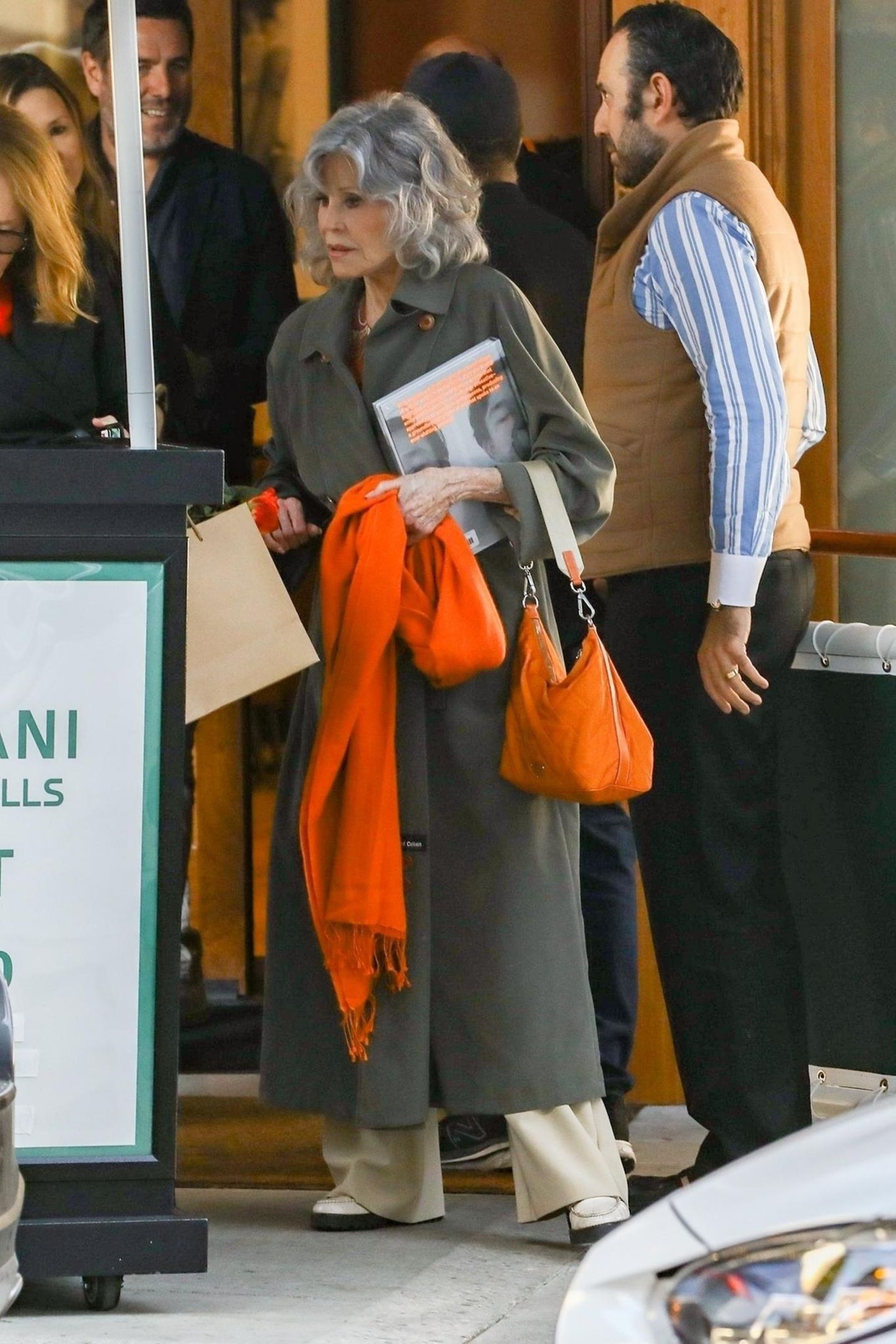 Sie weiß einfach, wie es funktioniert! Jane Fonda kombiniert einen khakifarbenen Trenchcoat zu knalligen orangen Accessoires und beweist dadurch ihr fantastisches Gespür für Mode und Farbkombinationen.