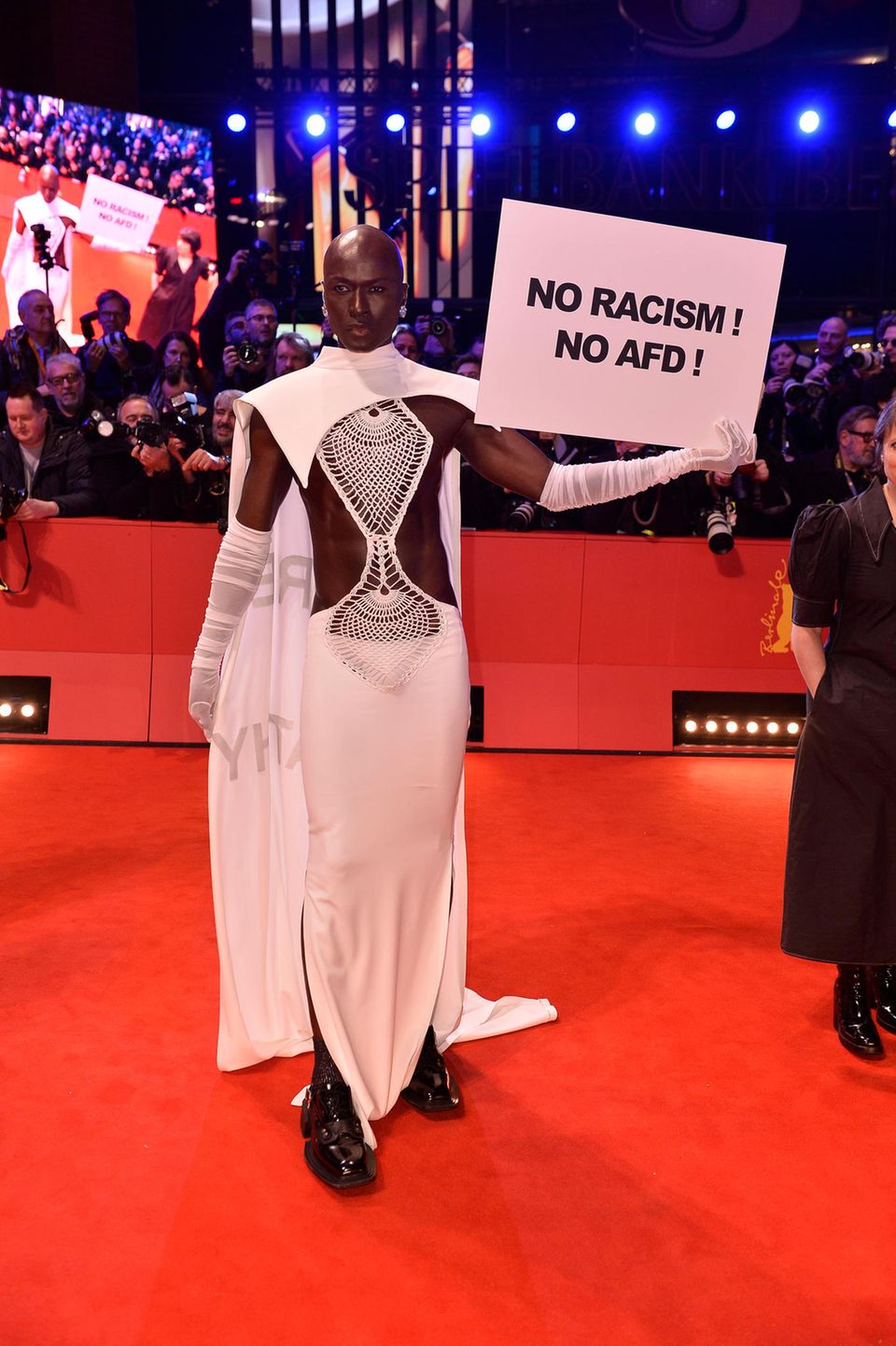 Papis Loveday lässt nicht nur sein Outfit sprechen. In der linken Hand hält das Model ein Schild, das eine eindeutige Sprache spricht: "No Racism! No Afd!".