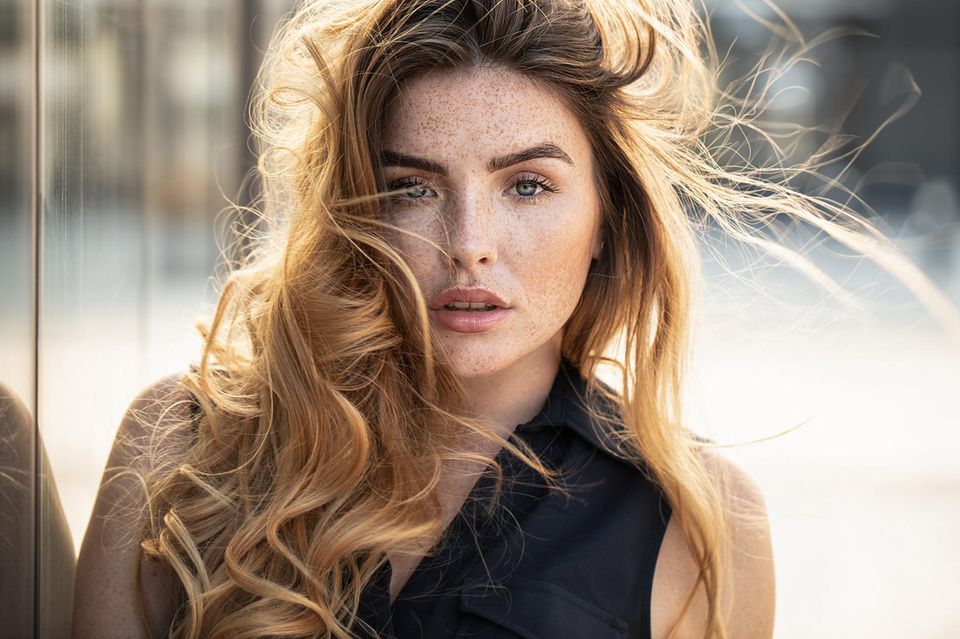 Blowout hair: Portrait einer jungen Frau mit voluminösem Haar im Wind