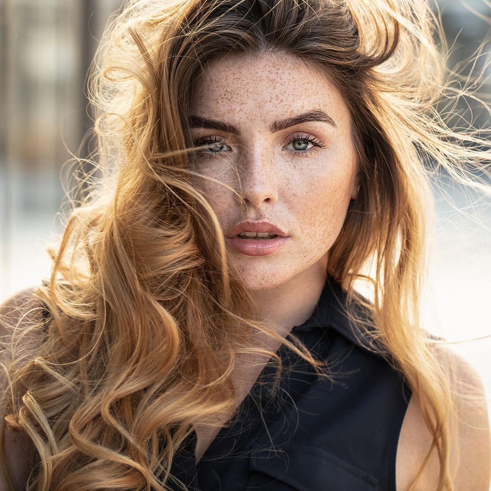 Blowout hair: Portrait einer jungen Frau mit voluminösem Haar im Wind