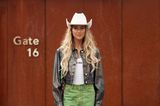 Ganz im Western-Look besucht Emili Sindlev die Alberta Ferretti Show in Mailand. Sie trägt einen weißen Cowboyhut, eine gecroppte Lederjacke in Holo-Optik, ein Miu-Miu-Top und eine grüne Jeans. Zebra-Schuhe machen das Outfit komplett. 