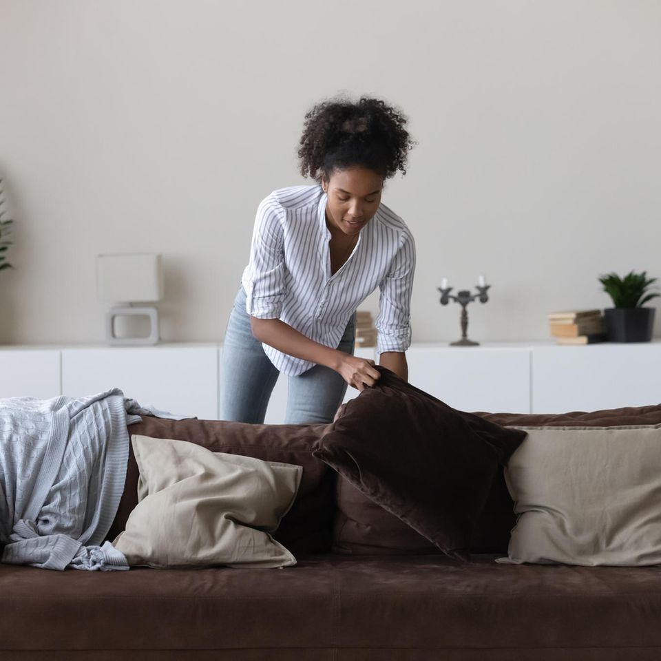 Frau räumt ihr Wohnzimmer auf: Speed Cleaning: Mit diesem Trick wird deine Wohnung in nur 8 Minuten sauber