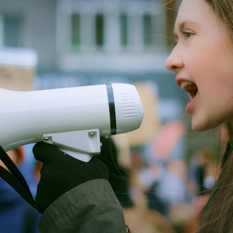 Frau schreit in ein Megafon auf einer Demonstration