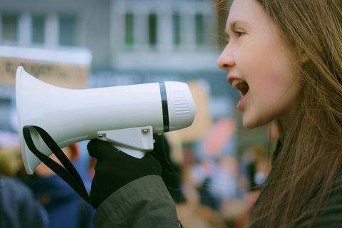 Frau schreit in ein Megafon auf einer Demonstration