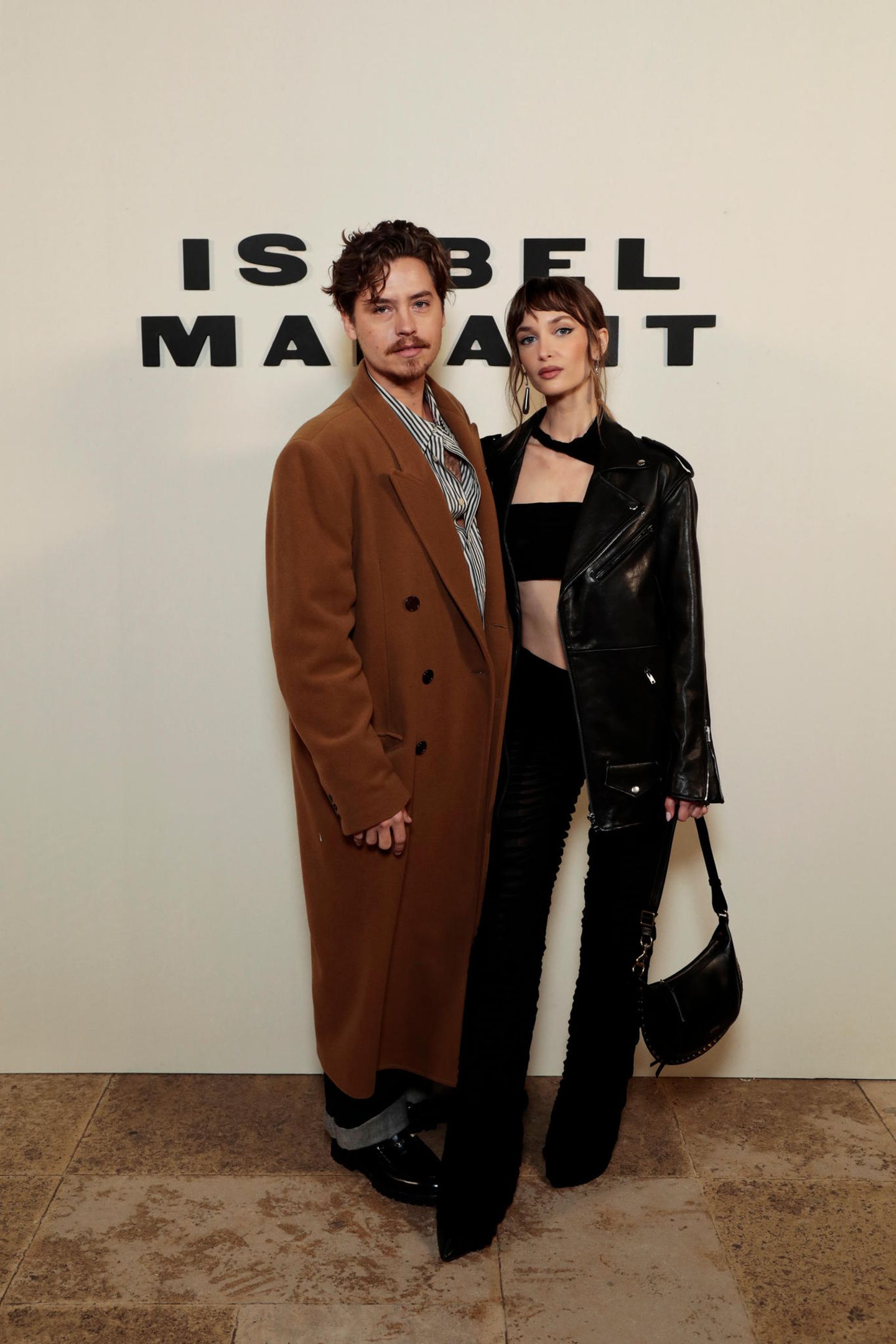 Strike a pose! Cole Sprouse und seine Freundin Ari Fournier sind Fans von Kontrasten: Das Model wählt einen Leder-Look in Schwarz, der Schauspieler inszeniert ein blaugestreiftes Hemd, das er relativ offen geknöpft hält. Brauner Mantel dazu, fertig!