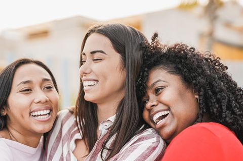 Drei Freundinnen umarmen sich lachend: 5 Gewohnheiten von Menschen, mit denen wir uns gern umgeben