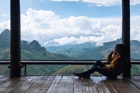 Frau schaut nachdenklich in die Berge: Dieser Denkfehler hindert dich daran, zu wachsen