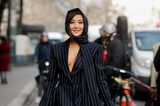 Im ultraknappen Nadenstreifen-Blazer mit passendem langem Schal sorgt "Emily in Paris"-Star Ashley Park auf dem Weg zur Show von Nina Ricci für Aufsehen.