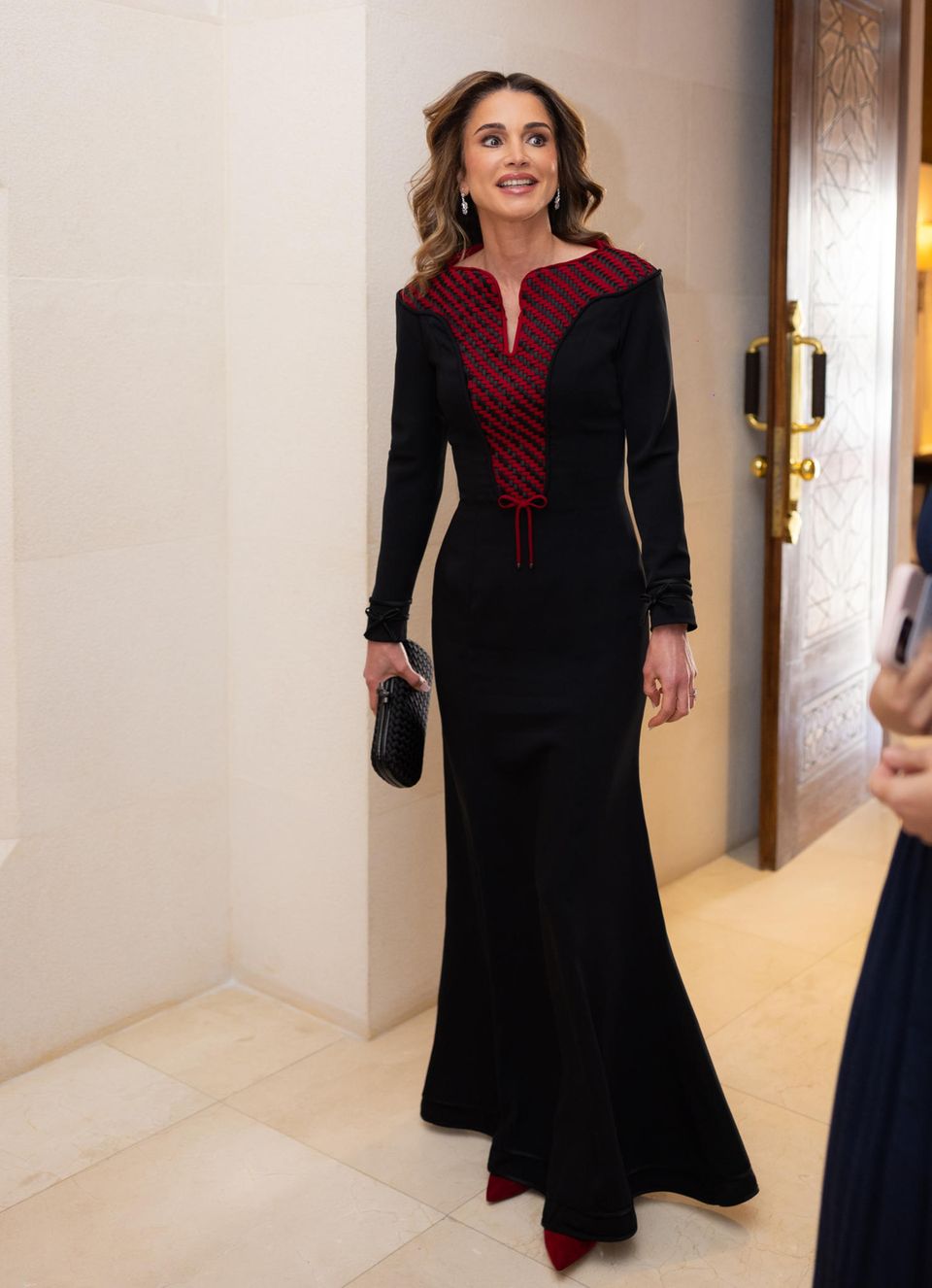 Elegant in Rot und Schwarz: Königin Rania legt bei ihrer Ehrung des Ordens der Renaissance im Al Husseiniya Palast einen glamourösen Auftritt hin. Für diesen Anlass trägt die Königin ein langes schwarzes Kleid mit geometrischer roter Strickerei am Ausschnitt und eine passende schwarze Bottega Veneta Clutch. 