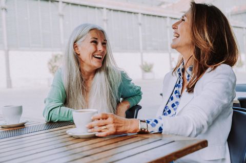 Zwei Freundinnen lachen beim Kaffeetrinken | Happy mit Ü50: 5 Tipps für mehr Zufriedenheit im Alter