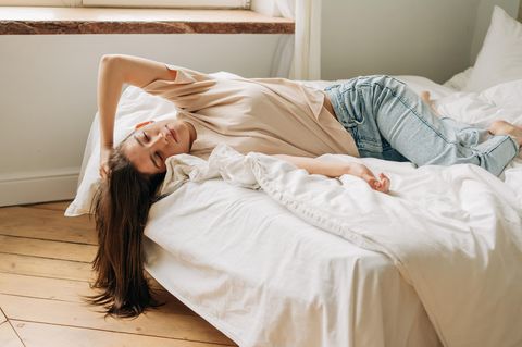 Hochsensibilität: Erschöpfte, junge Frau liegt auf einem Bett