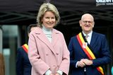 In einem stylischen, altrosafarbenen Mantel besucht Königin Mathilde von Belgien die Kinder- und Jugendabteilung der psychiatrischen Klinik Het Medisch in Bilzen. Unter dem Mantel trägt sie ein Ensemble aus Grautönen und kombiniert dazu ebenfalls graue Pumps und Perlenohrringe.