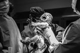 Geburtsfotografie 2024: Neugeborenes Baby wird vom Ärzteteam gehalten