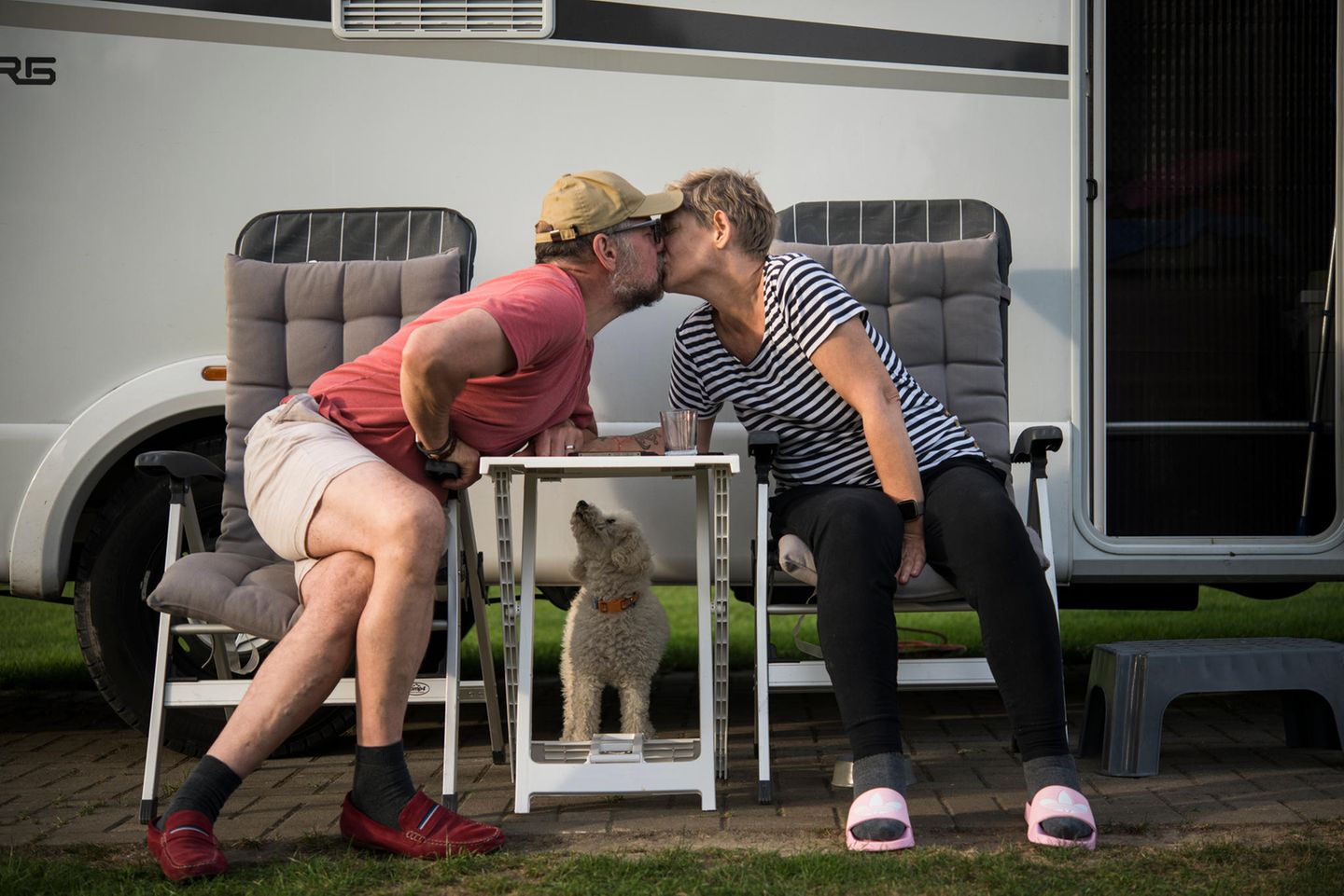 Hallo und Auf Wiedersehen: Paar küsst sich vor Wohnmobil
