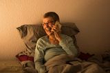 Hallo und Auf Wiedersehen: Frau sitzt im Bett und telefoniert