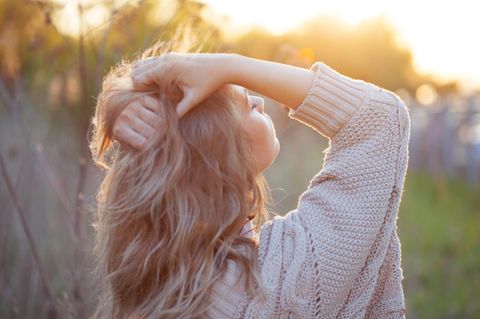 Frau mit geschlossenen Augen fasst sich in die Haare: Das sind die 2 wichtigsten Wörter für deine mentale Gesundheit