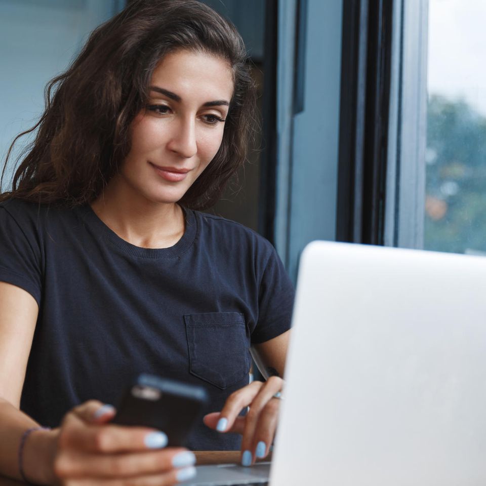 Altersvorsorge und ETF: Junge Frau schaut in einen Laptop und hat ein Handy in der Hand