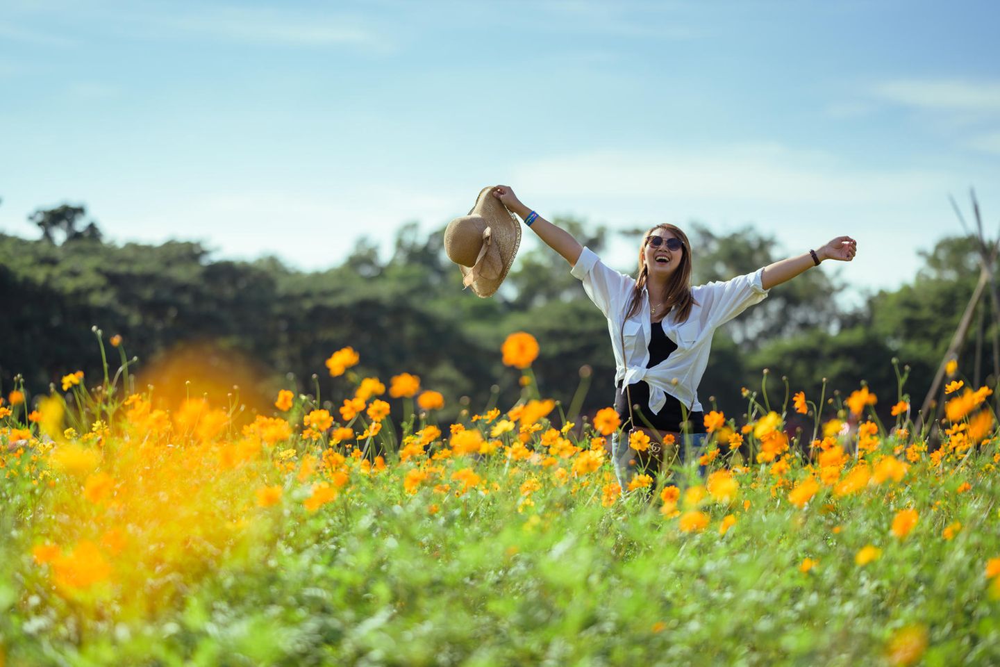 Horoskop ab 21.4.: Eine fröhliche Frau in einem Blumenfeld