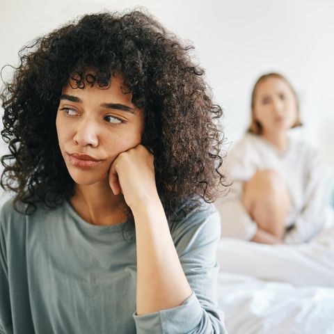 Grenzen setzen: Junge Frau sitzt frustriert auf einem Bett