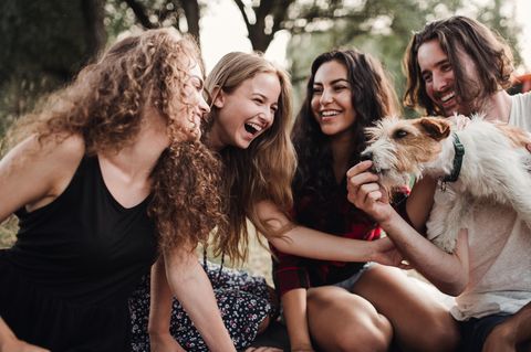 Zillennials: Eine Gruppe junger Freunde auf der Wiese mit einem Hund