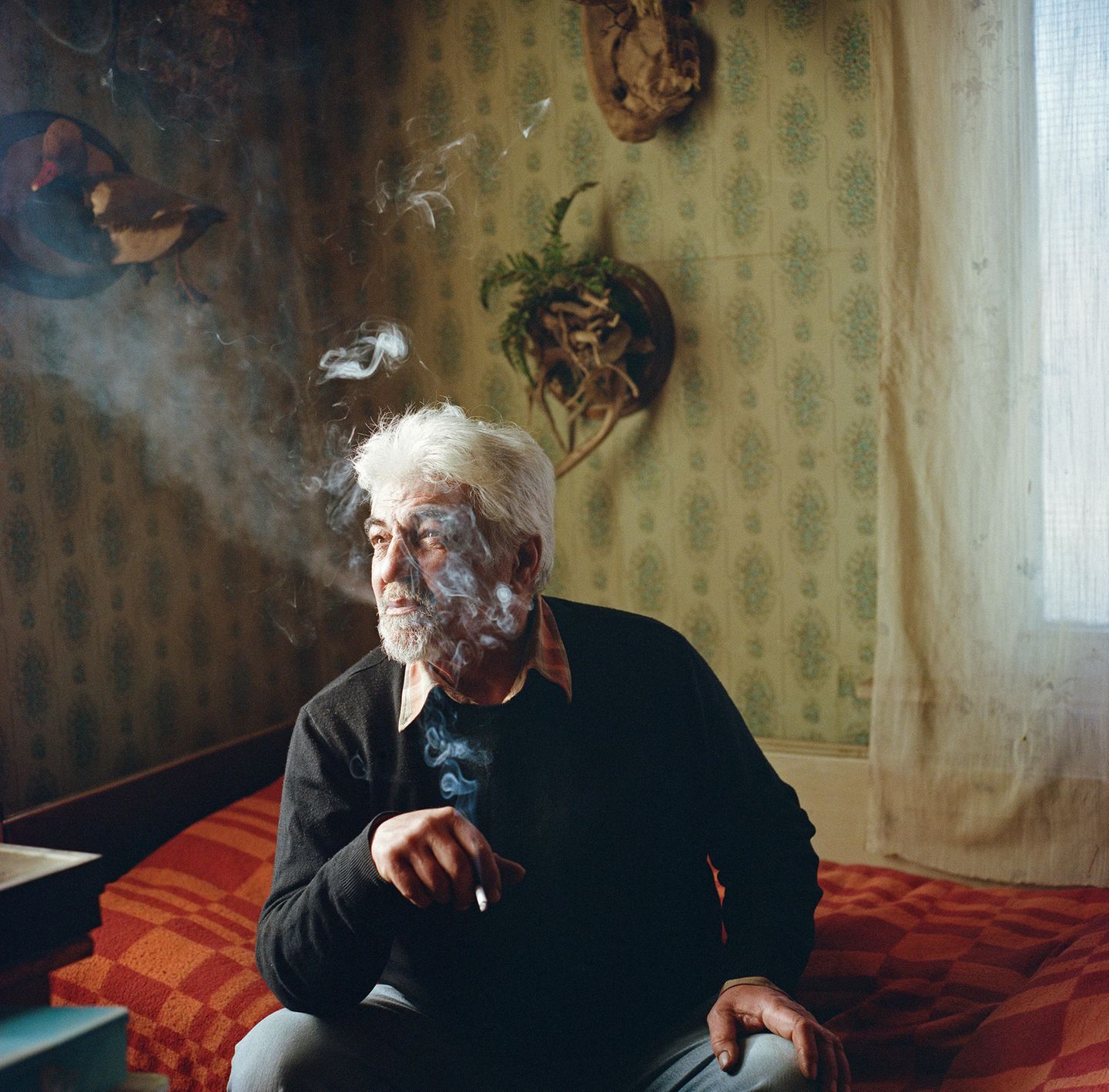 World Press Photo 2024: Mann raucht auf Bett sitzend