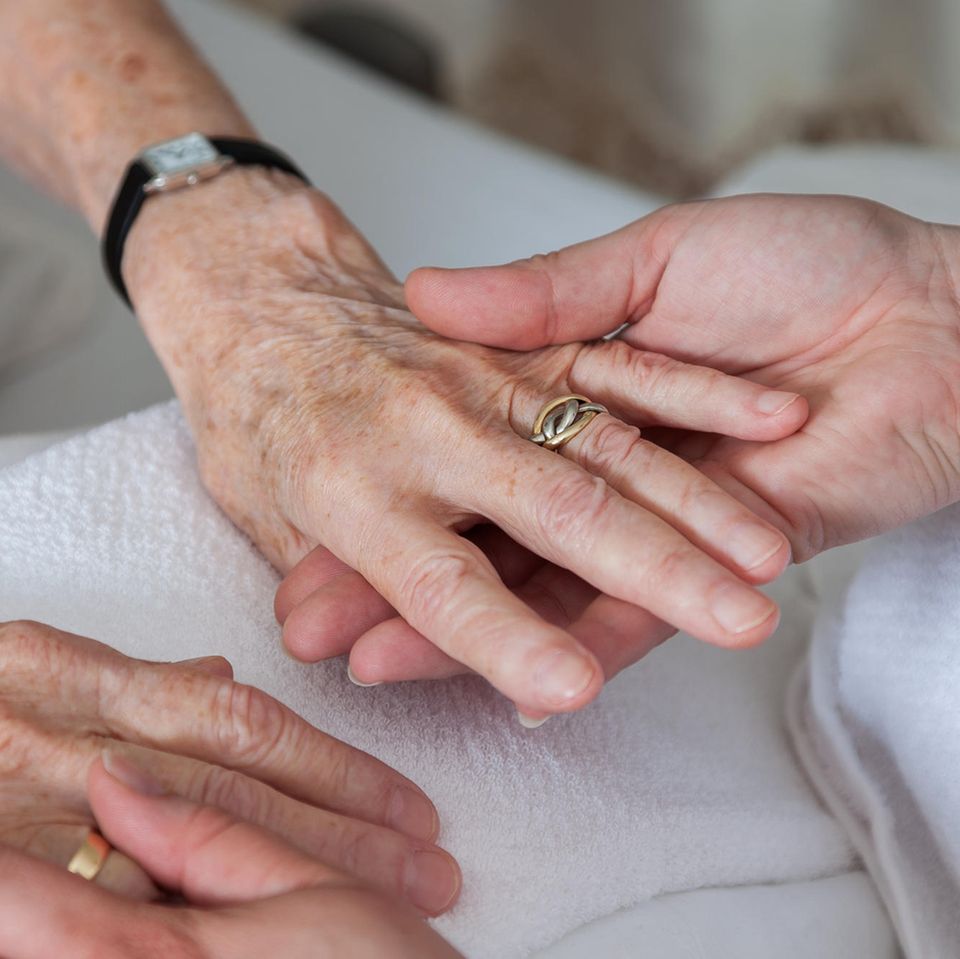 Pflege zu Hause: Zwei Hände halten die Hände einer älteren Dame