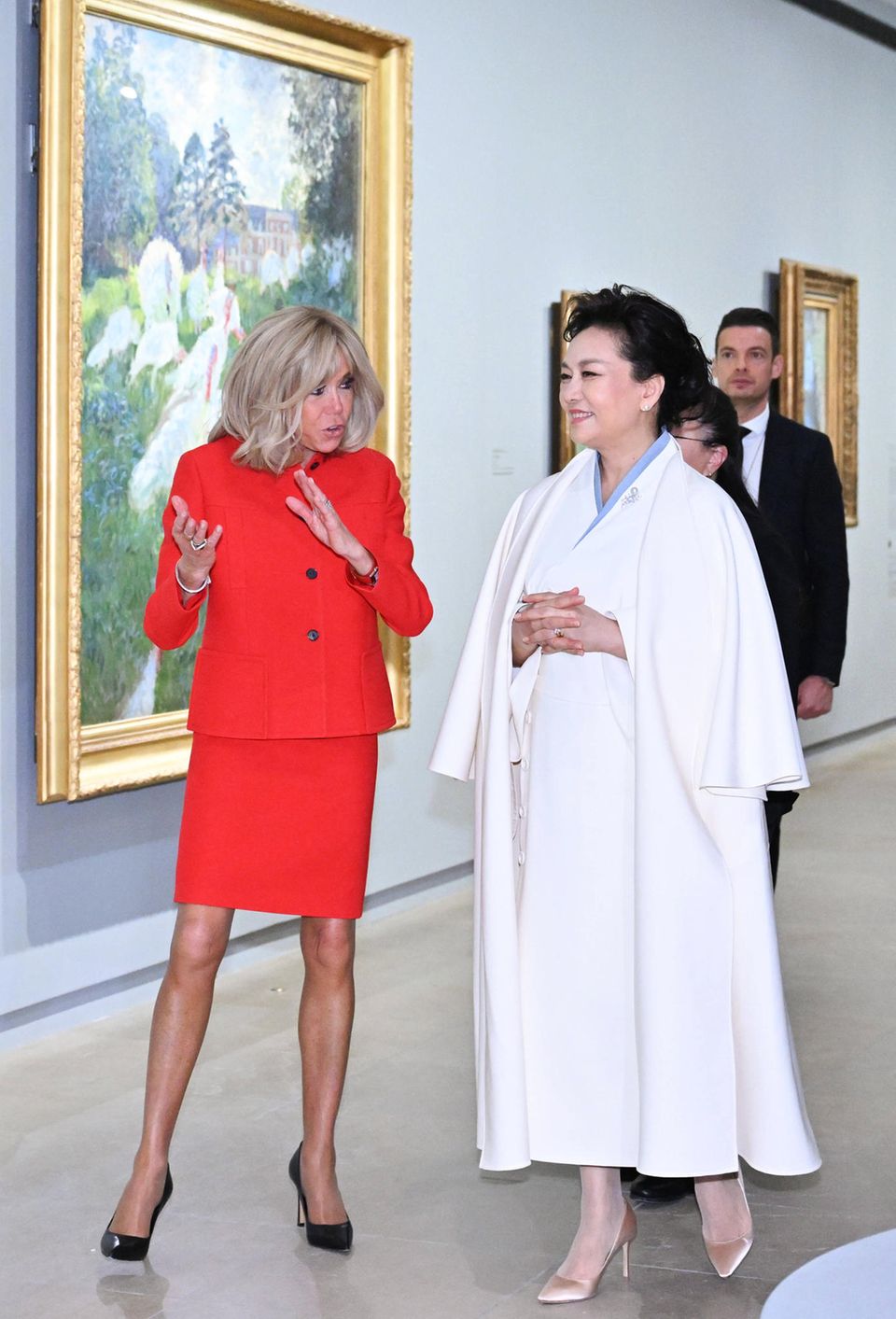 Nach dem ersten Empfang des Staatsbesuchs aus China geht es für die beiden First Ladys gleich auf einen kulturellen Ausflug ins Musée D'Orsay. Während Brigitte Macron in einem roten Dior-Ensemble leuchtet, zeigt sich Peng Liyuan in einem traditionellem Outfit in Weiß mit eleganten Mantel darüber