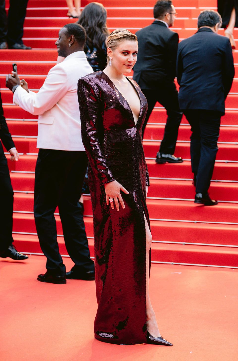 Regisseurin Greta Gerwig gehört in diesem Jahr zur Cannes-Jury. Ihr tiefweinroter Pailletten-Look für die Eröffnungszeremonie fällt dementsprechend glamourös aus. Das Kleid wurde für sie von Saint Laurent angefertigt.