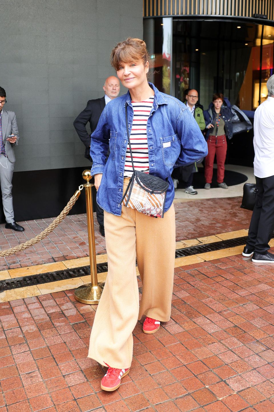 Ganz gemütlich gestylt mit Streifenshirt, Jeanshemd darüber, weiter Twillhose und Oldschool-Sneakern zieht es Supermodel Helena Christensen in die kleine Stadt.