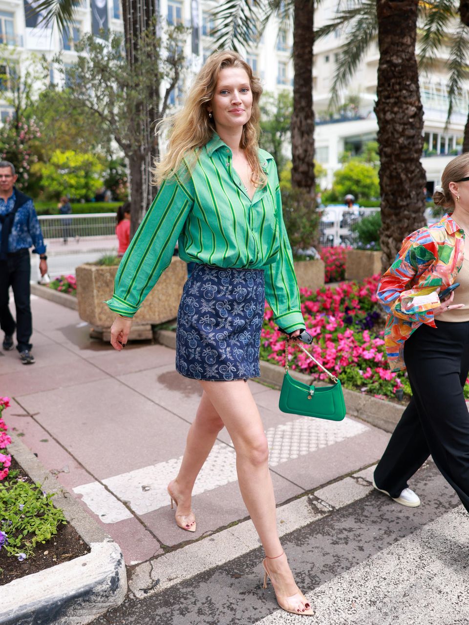 Colour-Blocking und Muster-Mix: Topmodel Toni Garrn trägt zu ihrem gemusterten Rock von Etro ein grünes Streifenhemd, transparente Heels und eine grüne Mini-Bag. Die sommerlich blonden Mähne trägt sie offen.