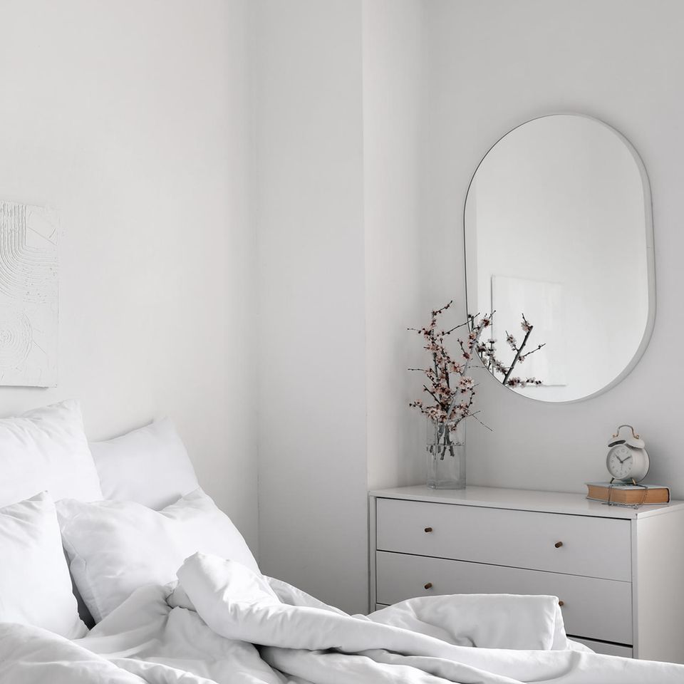 kleines Schlafzimmer: Bett und Kommode sowie ovaler Spiegel