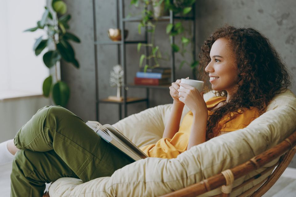 Frau trinkt zufrieden einen Tee und lächelt: 5 Dinge, für die du niemandem eine Erklärung schuldest
