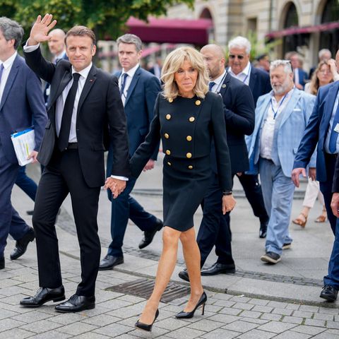 Brigitte Macron ist eine Meisterin darin, ihre Landesfarben dezent in Outfits zu integrieren. Neben Weiß kommen auch rote Details häufig zum Einsatz. Diesmal ist jedoch ein sattes dunkles Blau in Form eines Kostüms aus langärmeliger Jacke und knielangem Rock an der Reihe. Goldene Knöpfe, die das Blond ihrer Haare aufgreifen, verleihen dem Look schlichte Klasse.