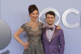Daniel Radcliffe und seine Partnerin Erin Darke sind bei den Tonys Awards bester Laune. Trotz Pailletten-Traumkleid sticht Daniels lilafarbener Anzug farblich noch mehr hervor. Obwohl beide verschiedene Farben tragen, bewegen sie sich dennoch in der gleichen Farbfamilie und bilden eine klare Einheit. Beide Looks sind von Todd Snyder. 