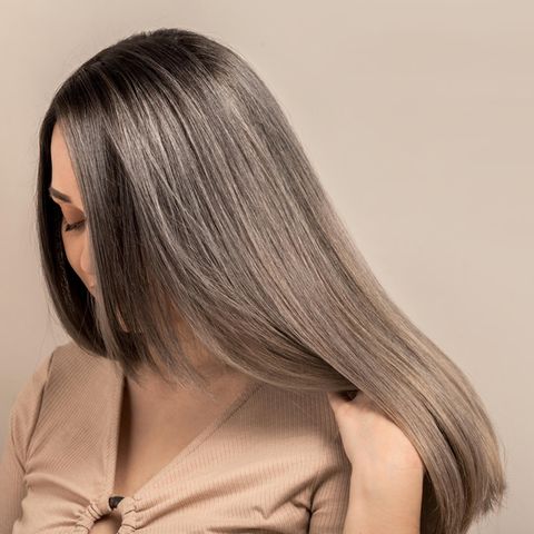 Grey Blending: Eine Frau mit grauen Strähnen zeigt ihre Haare
