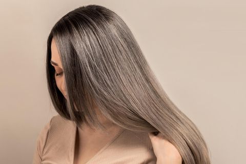 Grey Blending: Eine Frau mit grauen Strähnen zeigt ihre Haare