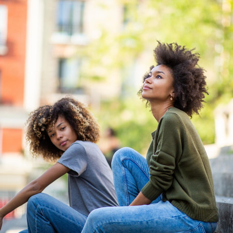 Zwei Frauen sitzen draußen auf einer Treppe: 3 Tipps, wie du es schaffst, weniger verurteilend zu sein