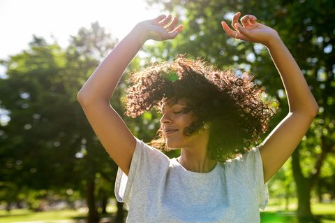 Glückliche Frau tanzt in der Natur: 5 Dinge, über die erfolgreiche Menschen sich nicht ständig Gedanken machen